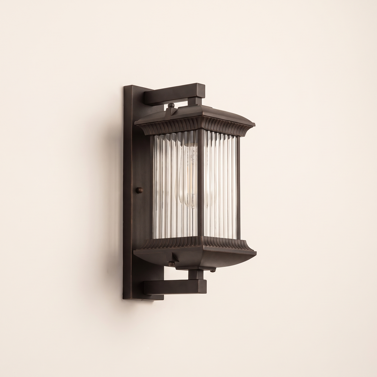 Dark bronze ribbed glass wall lantern on a plain off-white wall