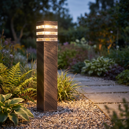 Bronze aluminium path bollard light in a gravel border at dusk