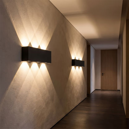 Two of the same wall lights along an interior hallway at night