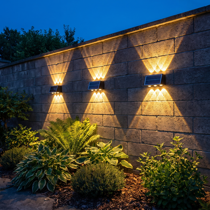 Three of the same lights spaced along a garden wall at blue hour