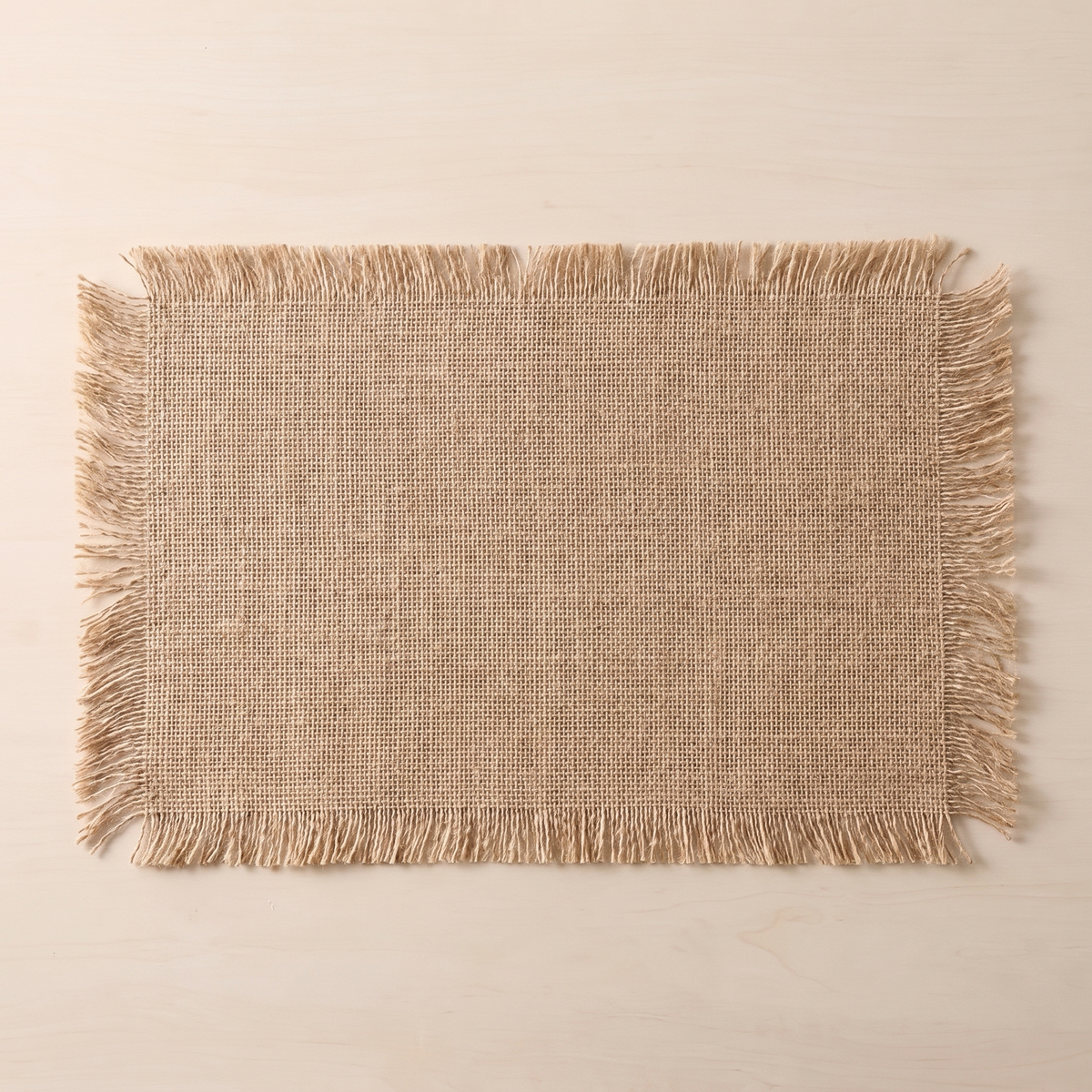 Overhead view of a single fringed jute placemat